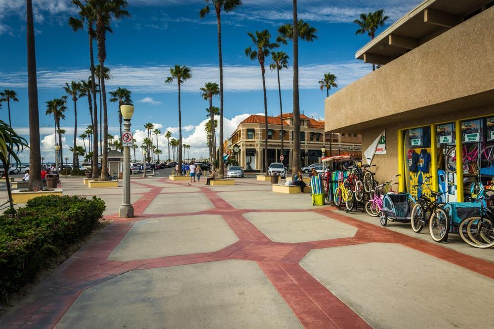 Walk along the pier and watch surfers ride waves on a sunny summer trip.