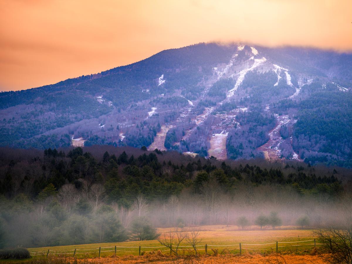 Mount Ascutney Summit and ski slopes and trails covered with snow at foggy wintry sunrise in Windsor, Vermont, USA