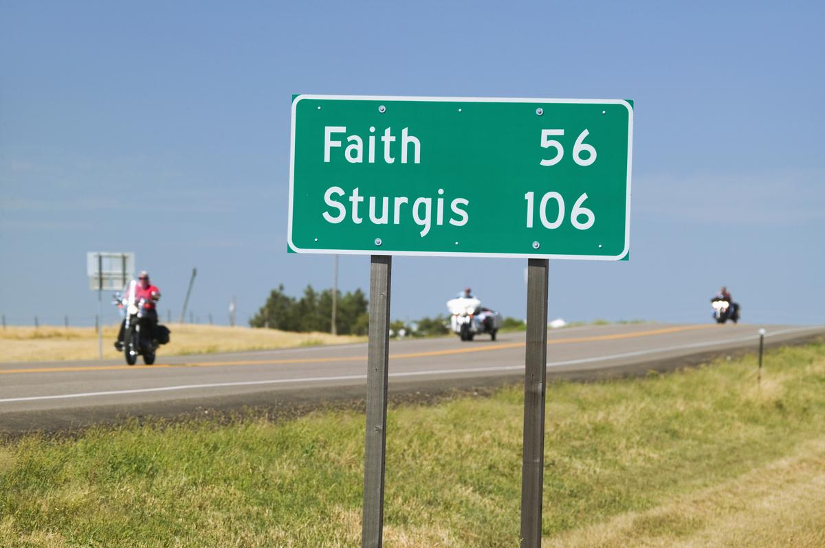 State Highway 34 with highway sign for Sturgis South Dakota and motorcyclist's heading away