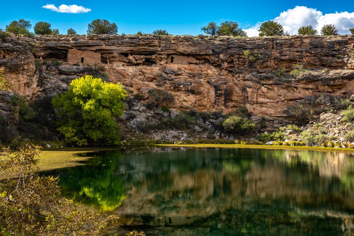 Ancient ruins and surroundings reflect on the quiet water of Montezuma Well