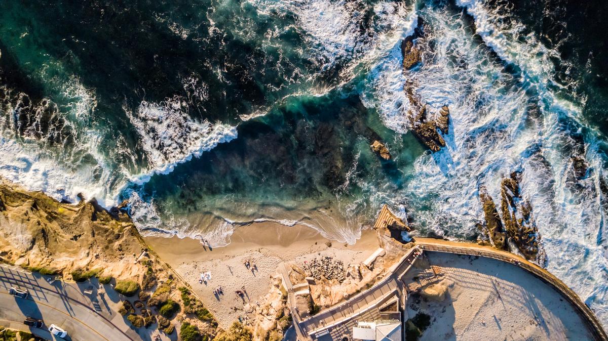 Enjoying waves hitting the rocks and the beach at seashore alongside a park in La Jolla San Diego